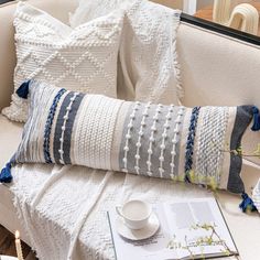 a white couch with two pillows and a book on it