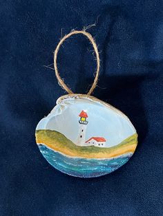 a ceramic ornament with a lighthouse on it's side hanging from a rope