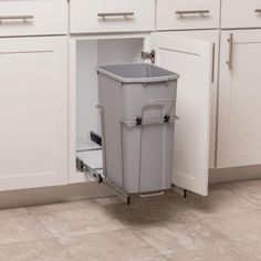 a trash can sitting inside of a kitchen next to white cupboards with drawers on each side