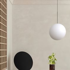 a white ball hanging from the ceiling next to a table with a potted plant