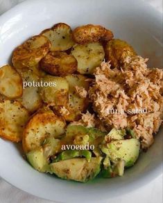 a white bowl filled with potatoes, broccoli and other food items on top of a table