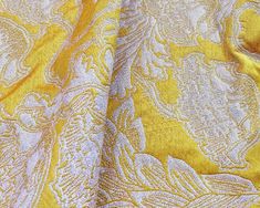 the yellow and white fabric has an intricate design on it's side, as well as