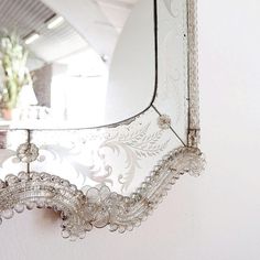 an ornate mirror hanging on the wall next to a potted plant