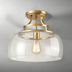 an image of a flush light fixture with clear glass on the bottom and gold trim