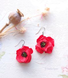 two red flowers sitting next to each other on top of a white cloth covered table