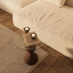 a table with two candles on top of it in front of a couch and rug