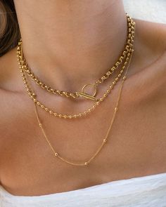 Our best-selling Olivia Necklace is a staple you need to elevate any look. It's a Double Layer Gold Plated Stainless Steel Ball Chain Necklace. Can be worn alone or paired with our Hailey Choker as seen. Gold Clavicle Chain Link Necklace, Dainty Gold Chain Round Necklaces, Dainty Round Chain Necklace With Adjustable Chain, Clavicle Link Chain Jewelry For Layering, Dainty Round Gold Chain Necklace, Gold Clavicle Chain Link Charm Necklaces, Gold Chain Necklace For Layering, Tarnish Resistant, Gold Link Clavicle Charm Necklace, Gold Plated Tarnish Resistant Link Necklace