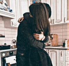 two people hugging each other in the kitchen