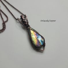 This STUNNING A+ purple rainbow labradorite pendant necklace features a two sided, copper wire wrapped design. The front features a beautiful yellow background with a purple rainbow, brilliant blues and hints of pink, peach, green and black. The reverse side has a bright yellow/orange base and a plash of purple and pink, with a brilliant blue lighting streak andhints of teal green and black, The copper and labradorite pendant is 3 inches tall and 7/8 inches wide. It has been buffed and polished, Iridescent Wire Wrapped Necklace For Gift, Iridescent Wire Wrapped Pendant Necklace, Spiritual Gemstone Necklace, Iridescent Labradorite Pendant Necklace, Iridescent Labradorite Pendant Jewelry, Iridescent Wire Wrapped Spiritual Jewelry, Iridescent Spiritual Wire Wrapped Jewelry, Handmade Iridescent Labradorite Necklace, Mystical Copper Pendant Jewelry