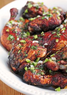 grilled chicken wings with green onions and seasoning in a white bowl on a wooden table