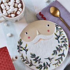 a santa clause plate sitting on top of a table next to a cup of coffee