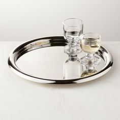 two wine glasses are sitting on a silver tray with a glass in the middle and one is empty