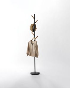 a coat rack with two hats on it and clothes hanging from the top, in front of a white background