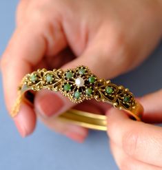 This is a beautiful gold-plated (vergoldet) bangle, created around the 1940s. The bangle features intricate detailing with a central floral motif. It is adorned with 10 jade stones and a central pearl. The design is reminiscent of the Victorian era. The bottom half of the bangle is plain, free of design. The bangle can be easily opened and closed with a box clasp, and an additional safety chain ensures it is secure and easy to put on and take off. Condition: Excellent vintage condition, with all Antique Gold Cuff Bracelet With 17 Jewels, Antique Yellow Gold Bracelets With Intricate Design, Victorian Style Yellow Gold Bracelets With Intricate Design, Victorian Bangle With Intricate Design For Formal Occasions, Vintage Yellow Gold Hallmarked Cuff Bracelet, Antique Yellow Gold Bracelet For Wedding, Formal Victorian Bangle With Intricate Design, Gold Victorian Cuff Bracelet With Intricate Design, Victorian Filigree Bracelets In Yellow Gold