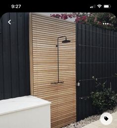 an outdoor shower in front of a wooden fence