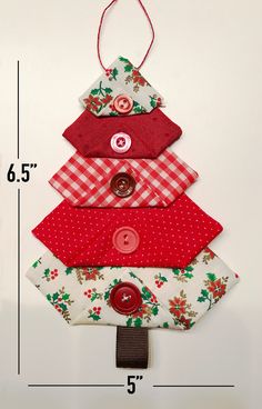 a christmas tree made out of fabric with buttons on the top and bottom, hanging from a wall