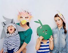 three children with paper masks on their faces and one child wearing a shark mask while the other girl wears a striped shirt