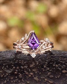 a ring with an amethorate and diamonds on it sitting on top of a rock