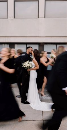 a bride and groom kissing in front of a group of people on their wedding day