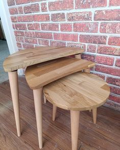 two wooden tables sitting on top of a hard wood floor next to a brick wall