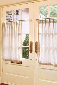 two white curtains hanging on the side of a door