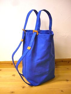 a blue handbag sitting on top of a wooden floor next to a white wall