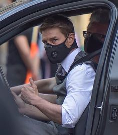 a man wearing a face mask sitting in a car