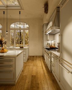 a large kitchen with wooden floors and white cabinets on both sides of the countertops