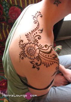 the back of a woman's stomach with henna tattoos on it and an image of