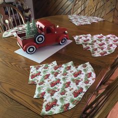 an old fashioned red truck with christmas trees on it sitting on top of a wooden table