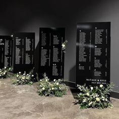 black and white wedding seating chart with flowers on the floor in front of two walls