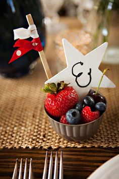 a bowl filled with berries and strawberries on top of a table next to silverware