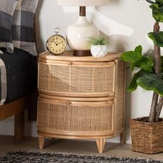 a wicker dresser with a clock and potted plants on it in front of a bed