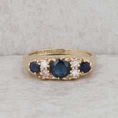 a three stone ring with blue and white stones on the sides, set in yellow gold