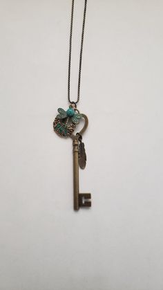 "This long charm necklace is a unique, interesting, and attractive gift for the special someone in your life. It features a bronze skeleton key, a recycled gold and turquoise earring, a patinaed dragonfly charm, a bronze feather charm,  and a small recycled turquoise bead. The assemblage dangles from a 30\" bronze box chain with a 3\" extender.  Welcome to Recycled Finery!  I repurpose old jewelry, coins, beads, vintage buttons, watch parts, and charms into new jewelry.  My ever-growing collection of these materials comes from estate sales, rummage sales, antique and thrift stores, and family and friends' collections they no longer need or want. I have fun putting these new pieces together and hope that you will find them fun to wear and as unique gifts for your loved ones.  Thank you for Bronze Jewelry With Lobster Clasp For Gift, Unique Vintage Charm Necklace As Gift, Unique Vintage Charm Necklace For Gift, Butterfly Charm Brass Jewelry Gift, Unique Brass Charm Necklaces For Gifts, Unique Brass Charm Necklaces As Gifts, Unique Bronze Charm Necklaces, Turquoise Dangle Charm Necklaces As Gift, Turquoise Dangle Charm Necklaces For Gifts