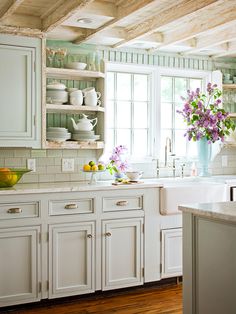 a kitchen filled with lots of white cupboards and counter top next to a window