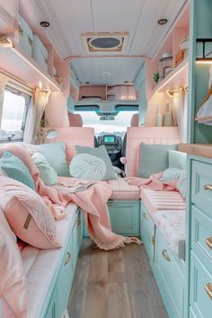 the interior of a pink and blue camper with lots of pillows on the bed