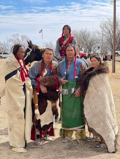 some people in native clothing standing next to each other and one is holding a horse