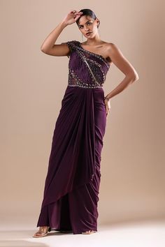 Burgundy lycra and net draped saree gown with Swarovski, crystals, cutdana and sequins hand embroidery. - Aza Fashions Pre-draped One Shoulder Floor-length Party Dress, Party Gown With Pre-draped Asymmetrical Neckline, One Shoulder Pre-draped Party Gown, Fitted Draped One-shoulder Wedding Dress, Party Asymmetrical Dress With Draped Sleeves, Asymmetrical Neckline Maxi Dress With Draped Sleeves For Party, Party Wear Pre-draped Maxi Saree, Party Maxi Length Pre-draped Saree, Party Maxi-length Pre-draped Saree