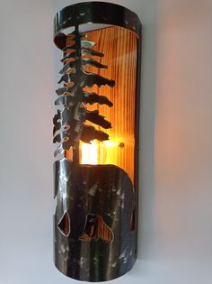 a wall mounted light with an animal on it's side and trees in the background