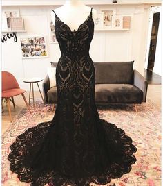 a black evening gown on display in a room with a couch and chair behind it