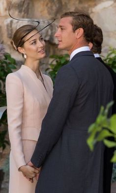 a man in a suit and tie standing next to a woman wearing a pink dress