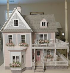 a doll house with flowers in the window boxes on the front and second story porch