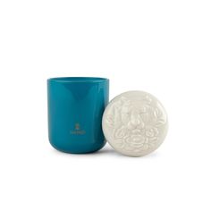 a blue cup with a white lid next to a teal colored mug that has a lion head on it