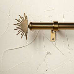 a close up of a curtain rod on a white wall with sunbursts