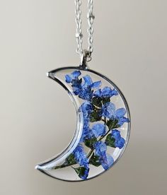 "This stunning Forget me not flower necklace is encapsulated in resin Moon open bezel.  The pendant is 0.60\" wide x 1.75\" high x 1/8\" thickness and come with a beautiful chain-length of your choice. The petals have been carefully preserved to retain their color and would make a great gift for your loved ones. This piece was made with real flowers and hence it is important to preserve the jewelry in the box provided safely away from direct sunlight.  You can see more of my Handmade Items here:  https://www.etsy.com/shop/Thecraftiechristie" Nature-inspired Resin Birth Flower Jewelry, Nature-inspired Birth Flower Resin Jewelry, Blue Flower Resin Jewelry, Unique Resin Flower Jewelry, Pressed Flowers Resin Jewelry As A Gift, Unique Flower-shaped Resin Jewelry, Resin Flower Jewelry With Flower Charm, Flower-shaped Resin Jewelry Gift, Unique Pressed Flower Jewelry