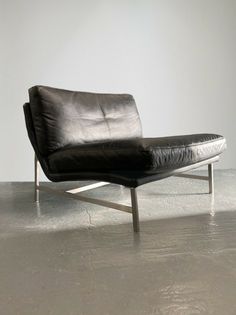 a black leather chaise lounge chair in an empty room