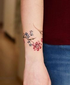 a woman's wrist tattoo with flowers on it