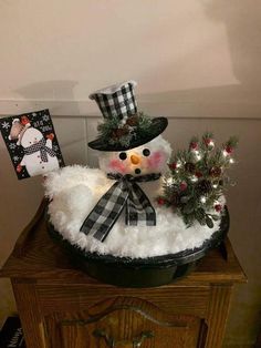 a snowman is sitting on top of a small table with christmas decorations and cards