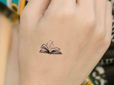 a person with a book tattoo on their left hand